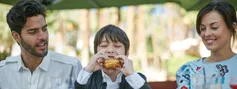 HTL-ORL Family Eating Sandwich At Table Outdoors